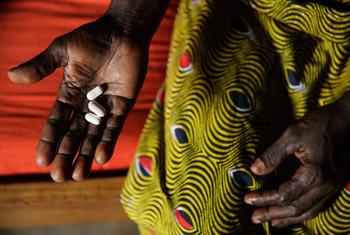 In Côte d’Ivoire, a woman living with HIV holds three pills she takes daily as part of antiretroviral therapy.