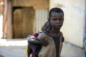 A child carries his younger sister on his back. Both children are living on the street in Aweil, South Sudan. UNICEF/Rich
